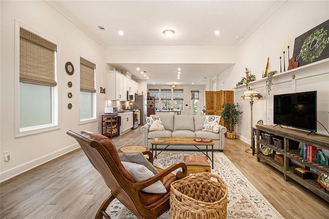 living area with crown molding, baseboards, and light wood finished floors
