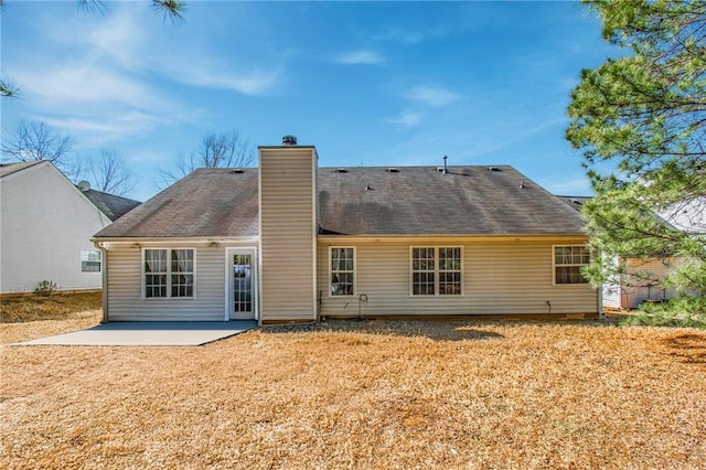 back of property featuring a patio area, a chimney, and a yard