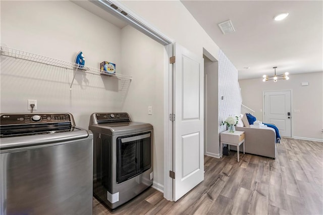 laundry room with an inviting chandelier, separate washer and dryer, and wood-type flooring