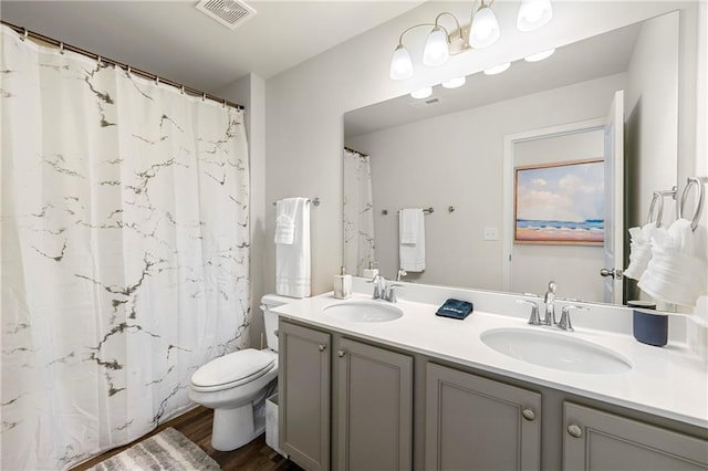 bathroom featuring toilet, hardwood / wood-style floors, and dual bowl vanity