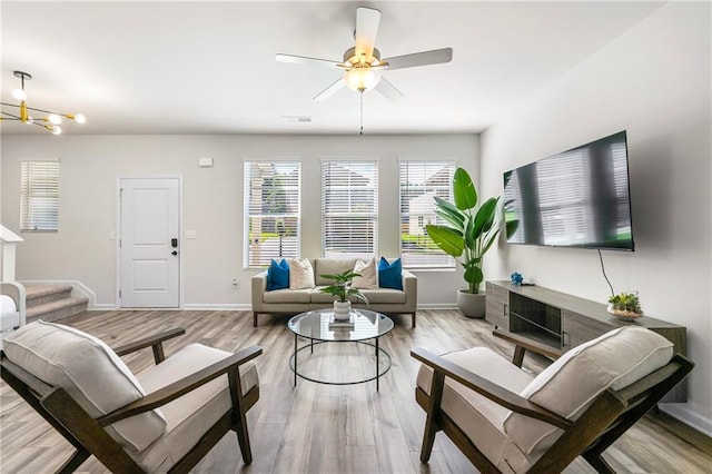 living room featuring light hardwood / wood-style floors and ceiling fan with notable chandelier