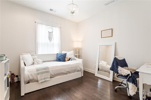 bedroom with an inviting chandelier, baseboards, wood finished floors, and visible vents