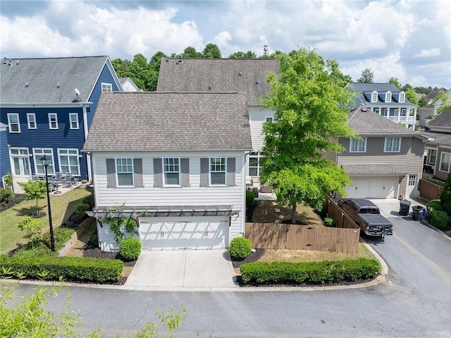 view of front of property featuring a garage, fence, driveway, and a residential view