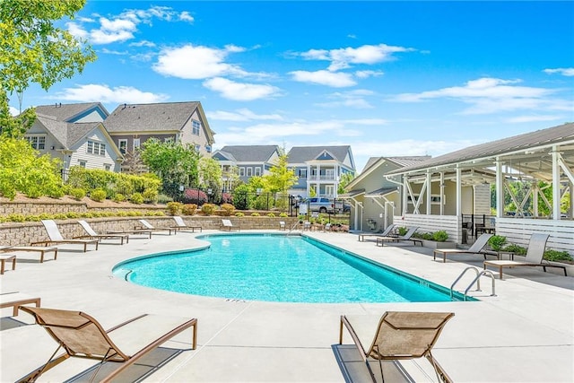 pool with a patio, fence, and a residential view