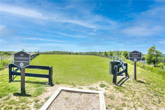 view of property's community with a lawn, a rural view, and fence