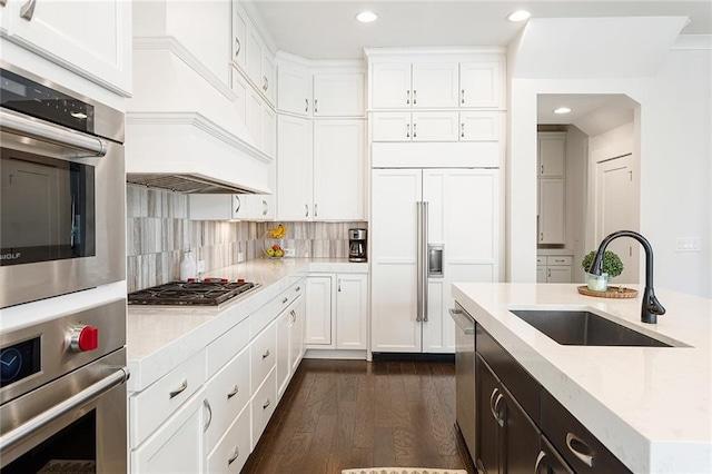 kitchen with dark wood-style flooring, stainless steel dishwasher, gas stovetop, a sink, and white cabinets
