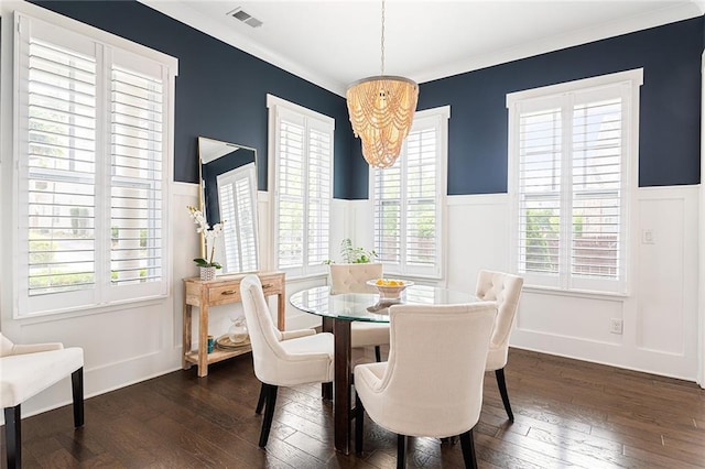 dining room with crown molding, dark wood-style flooring, a decorative wall, a wainscoted wall, and visible vents