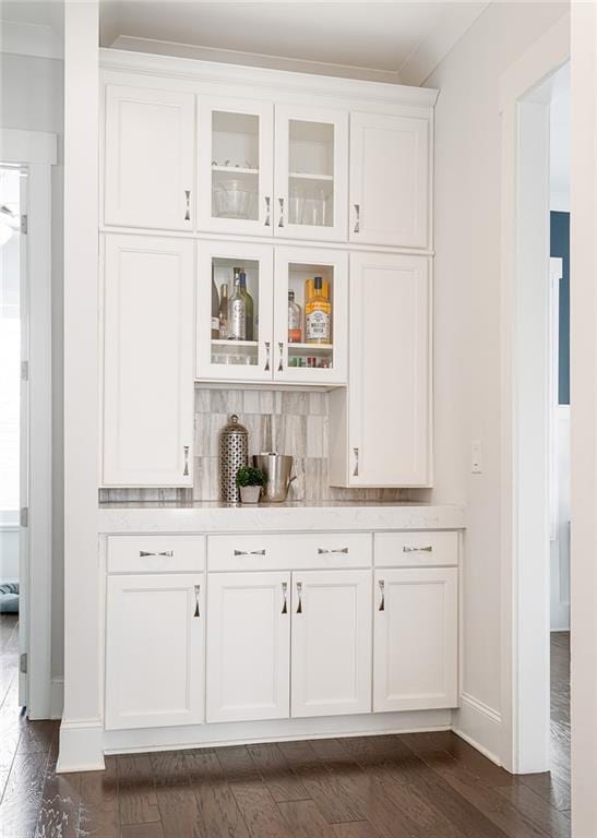 bar featuring baseboards, decorative backsplash, and dark wood finished floors