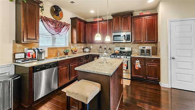 kitchen featuring hanging light fixtures, stainless steel appliances, a center island, dark hardwood / wood-style floors, and sink