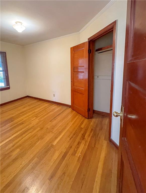 unfurnished bedroom with ornamental molding and light wood-type flooring