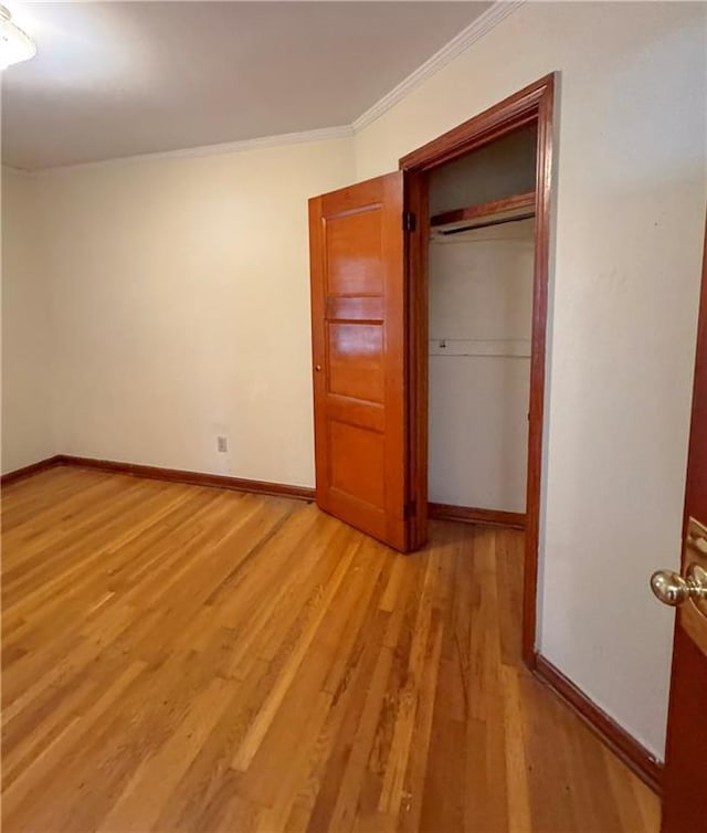 unfurnished bedroom featuring light wood-type flooring, ornamental molding, and a closet