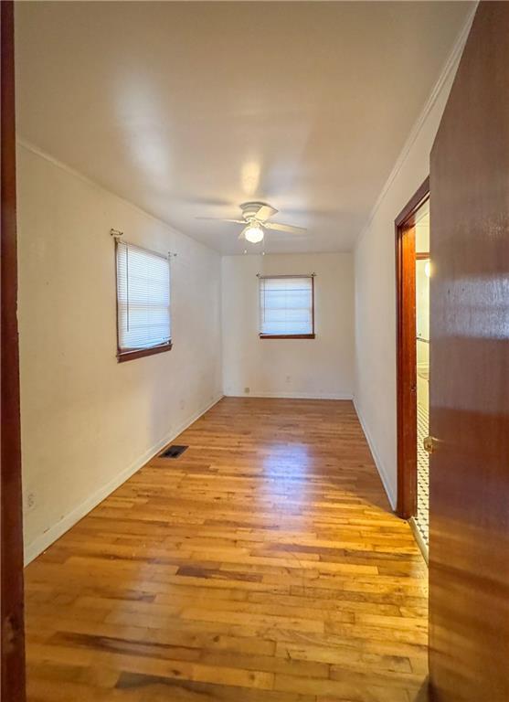 unfurnished room featuring ceiling fan, light wood-type flooring, and ornamental molding