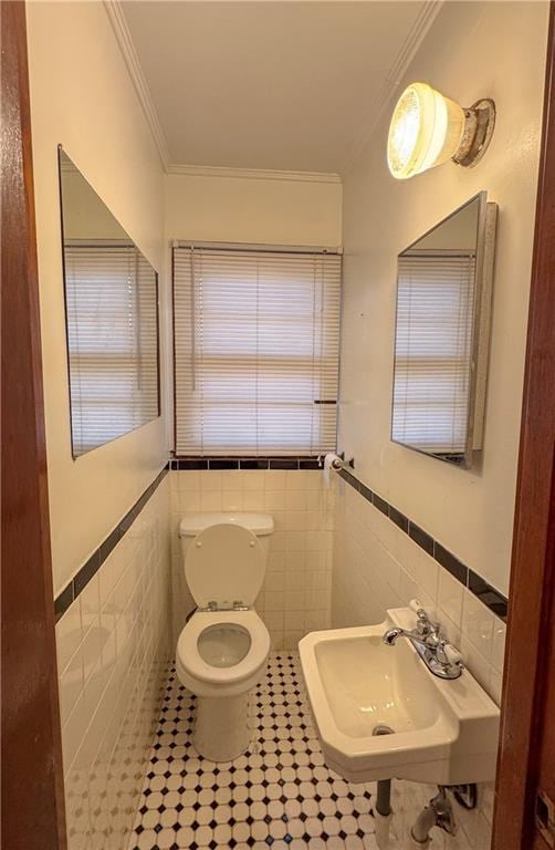 bathroom with tile patterned floors, sink, ornamental molding, and tile walls