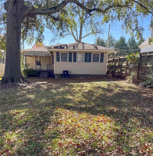 rear view of house with central AC and a lawn