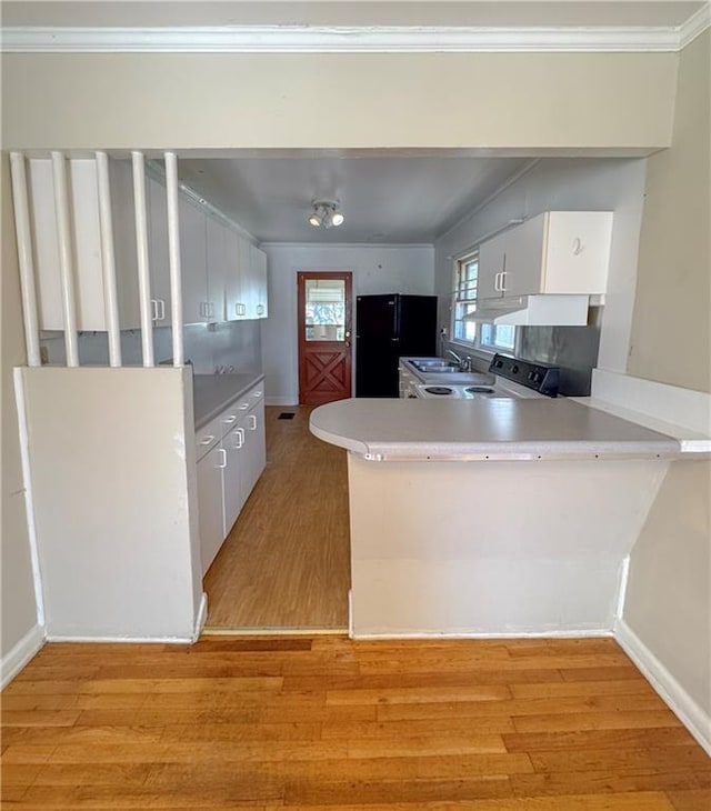 kitchen with black fridge, white cabinetry, kitchen peninsula, and light hardwood / wood-style flooring