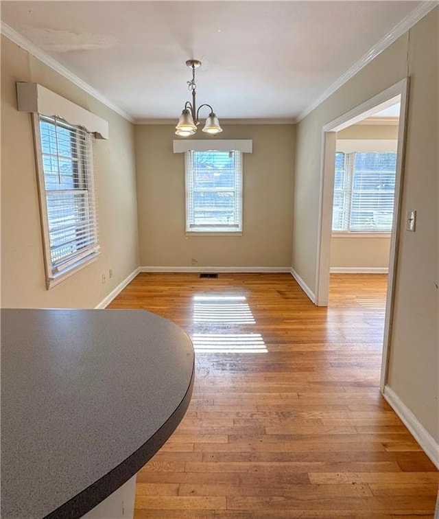 unfurnished dining area with wood-type flooring, an inviting chandelier, and ornamental molding