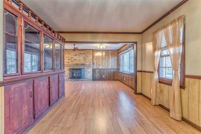 unfurnished living room with light hardwood / wood-style floors, wood walls, and crown molding