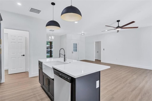 kitchen with light wood-type flooring, dishwasher, ceiling fan with notable chandelier, an island with sink, and hanging light fixtures