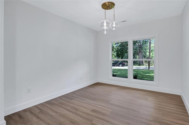 spare room featuring a notable chandelier and hardwood / wood-style floors