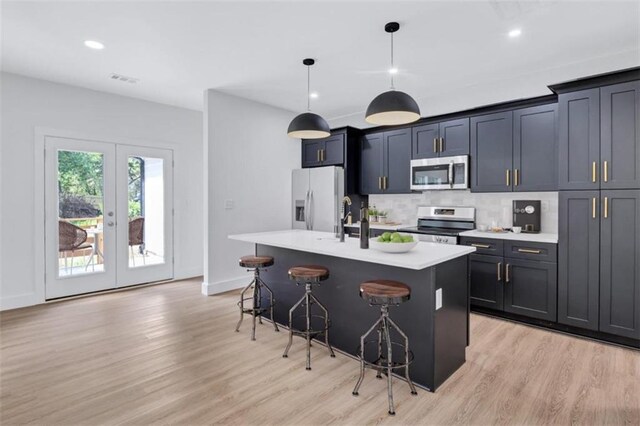 kitchen with light hardwood / wood-style flooring, a kitchen bar, a center island with sink, and fridge with ice dispenser