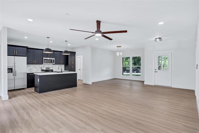 kitchen with backsplash, pendant lighting, an island with sink, stainless steel appliances, and hardwood / wood-style flooring