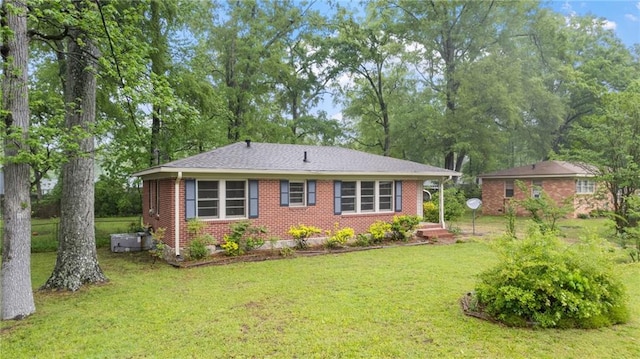 back of property with brick siding, a lawn, and view of wooded area