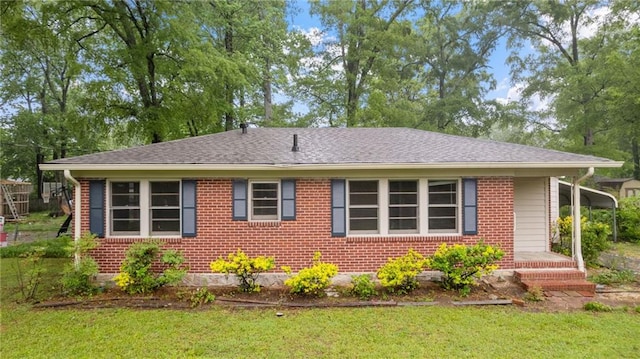 view of side of home featuring a lawn, brick siding, and a shingled roof