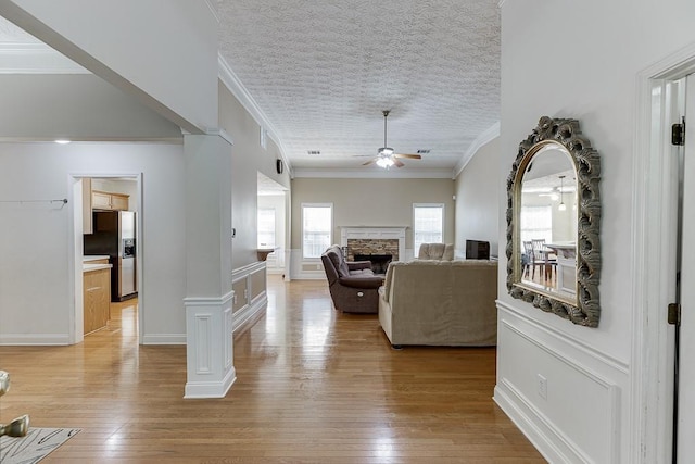 6485 Flowery Way, Flowery Branch, GA 30542 - living room with a ceiling fan, a fireplace, light wood-style floors, ornamental molding, and a textured ceiling