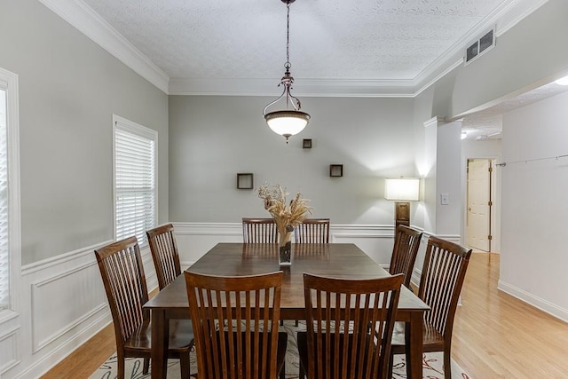 6485 Flowery Way, Flowery Branch, GA 30542 - dining space with light wood-style floors, crown molding, a wainscoted wall, and a textured ceiling