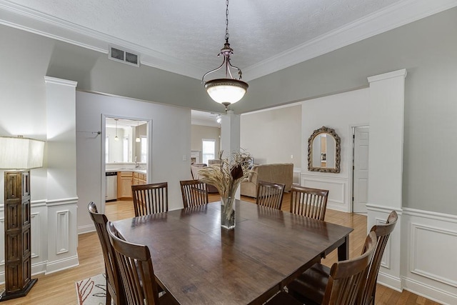 6485 Flowery Way, Flowery Branch, GA 30542 - dining area with a decorative wall, light wood-style flooring, crown molding, a wainscoted wall, and a textured ceiling