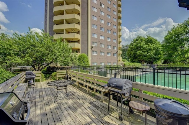 wooden deck featuring area for grilling and a fenced in pool