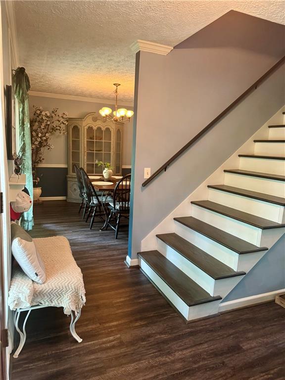 4114 Falcon Shores Ct NW, Acworth, GA 30101 - stairs featuring a textured ceiling, a chandelier, ornamental molding, and wood finished floors