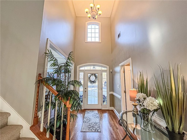 entryway with wood-type flooring, a high ceiling, and a chandelier