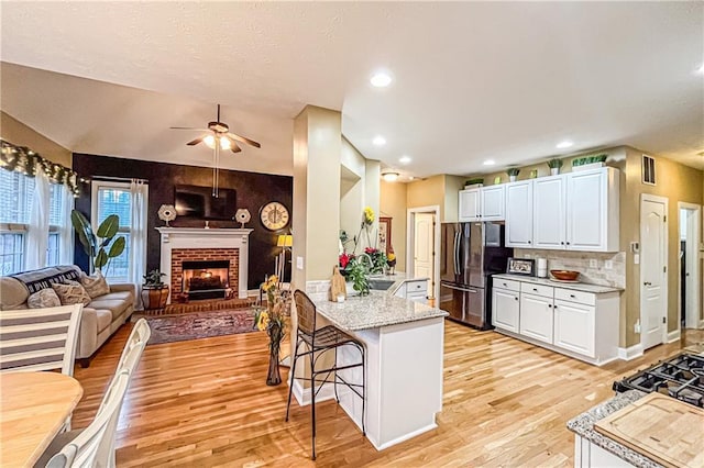 kitchen featuring kitchen peninsula, a kitchen breakfast bar, white cabinetry, and stainless steel refrigerator