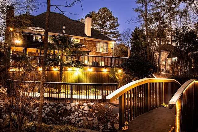 back house at dusk featuring a deck