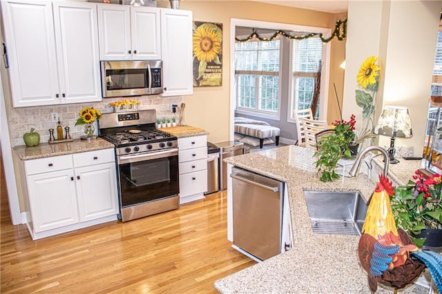 kitchen featuring white cabinetry, light stone counters, sink, and stainless steel appliances