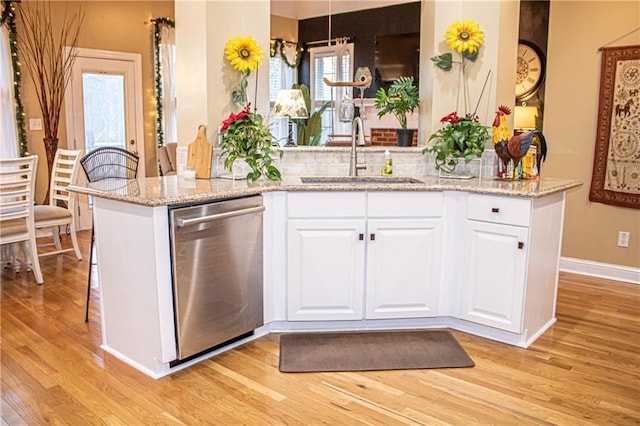 kitchen with white cabinets, kitchen peninsula, stainless steel dishwasher, and sink