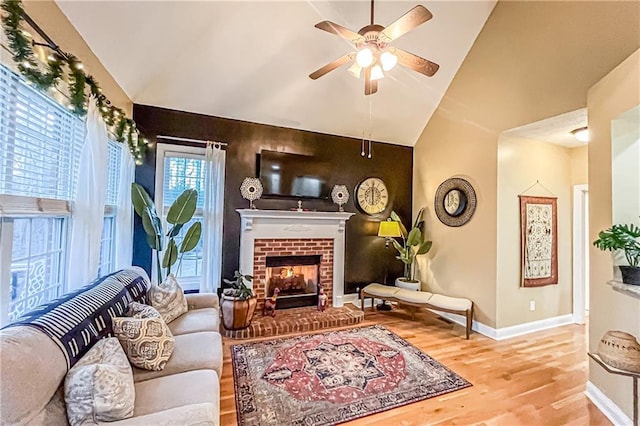 living room featuring hardwood / wood-style floors, ceiling fan, lofted ceiling, and a fireplace