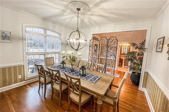 dining room featuring hardwood / wood-style flooring, a textured ceiling, crown molding, and a chandelier