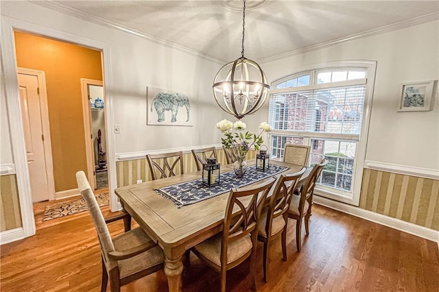 dining space with hardwood / wood-style floors, ornamental molding, and a notable chandelier