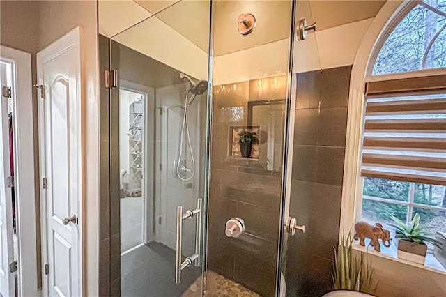 bathroom featuring a shower with door and a healthy amount of sunlight