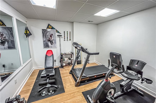 exercise room with a paneled ceiling and hardwood / wood-style flooring