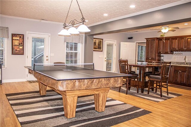 recreation room with ceiling fan, light hardwood / wood-style flooring, a textured ceiling, and ornamental molding