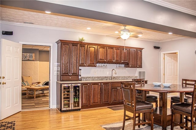 kitchen featuring ceiling fan, crown molding, beamed ceiling, light hardwood / wood-style floors, and wine cooler