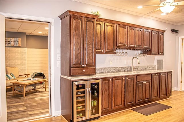 kitchen featuring ceiling fan, sink, wine cooler, light hardwood / wood-style flooring, and crown molding