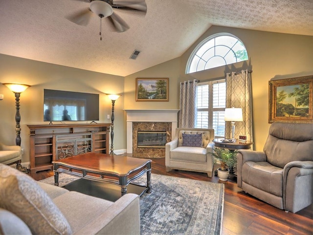 living area featuring a high end fireplace, visible vents, a textured ceiling, and vaulted ceiling