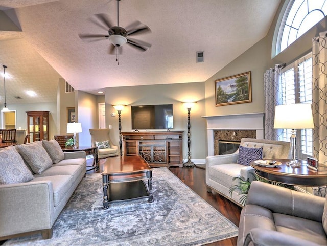 living room with a textured ceiling, visible vents, dark wood-style flooring, ceiling fan, and vaulted ceiling