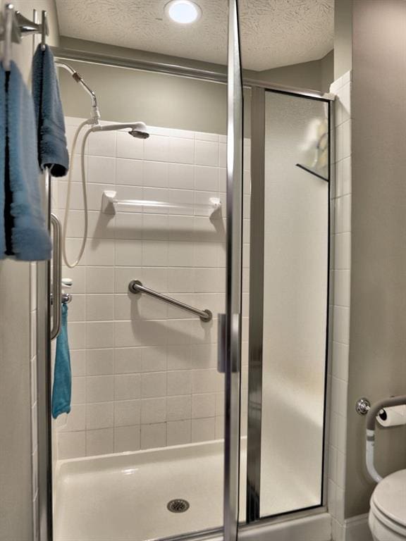 full bathroom featuring a stall shower, a textured ceiling, and toilet