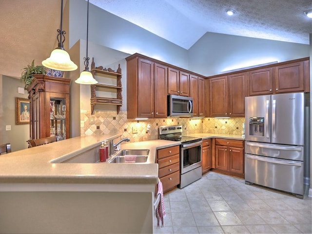 kitchen with lofted ceiling, a sink, a peninsula, light countertops, and appliances with stainless steel finishes
