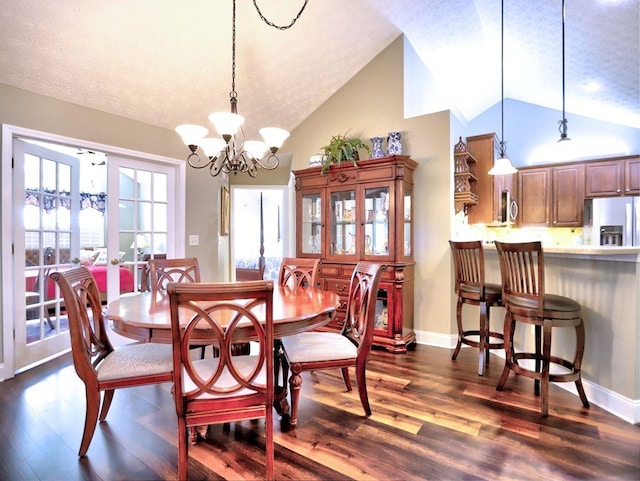 dining room featuring vaulted ceiling, a chandelier, a textured ceiling, and dark wood-type flooring